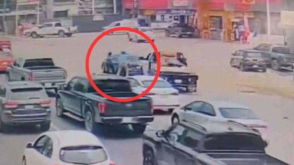 Two People Stand Beside a Blue Car at a Busy Urban Intersection; Many Vehicles Surround Them. - Nuevo León Primero