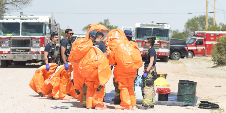 Img Destacadas 02 - 1200x675 - Nuevo León Primero Emergency Responders in Bright Orange Hazmat Suits Gather for a Briefing Near Fire Trucks in a Dusty Training Area. - Nuevo León Primero
