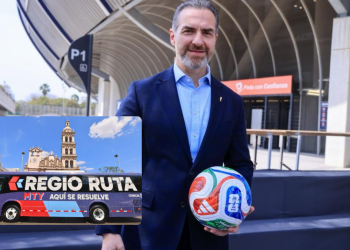 Man in a blue blazer holds a colorful soccer ball at a stadium entrance; inset shows a purple Regio Ruta bus with a church in the background.