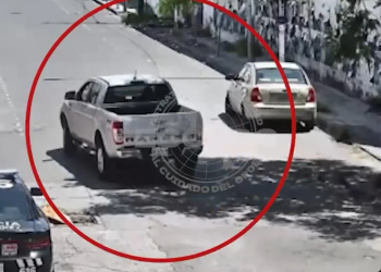 Surveillance Frame of a White Pickup Truck in the Middle of a Street, Circled in Red, with a Beige Car Nearby and Bystanders on the Sidewalk. - Nuevo León Primero