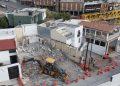a Demolition Site in a Residential Area: Rubble, a Small Backhoe on Debris, and Orange Traffic Cones by the Intact Surrounding Buildings. - Nuevo León Primero