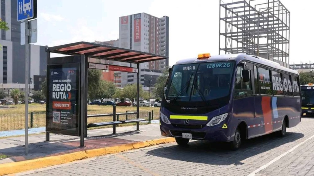 Blue City Bus with a Yellow Stripe at the Front Parked Beside a Modern Bus Stop in an Urban Area. - Nuevo León Primero