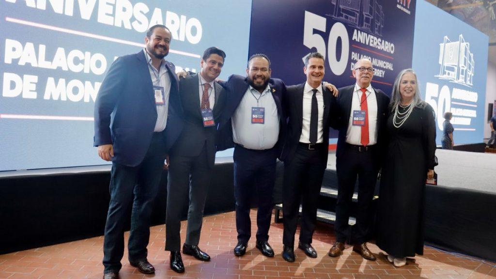 Dirigencia-del-pan-adrián - Nuevo León Primero Six Professionals Pose Together on a Stage During a 50th Anniversary Event, Badges Visible, with a Large Blue Backdrop Reading '50 Aniversario' in the Background. - Nuevo León Primero