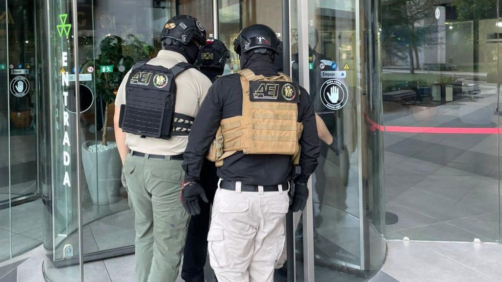 Security Personnel in Tactical Vests and Helmets Entering a Glass Door at a Modern Building Lobby (entrada Sign Visible). - Nuevo León Primero