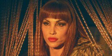 Portrait of a Woman with Red Hair and Bold Makeup, Wearing a Fur Collar, Gazing at the Camera with Gold String Lights in the Background. - Nuevo León Primero