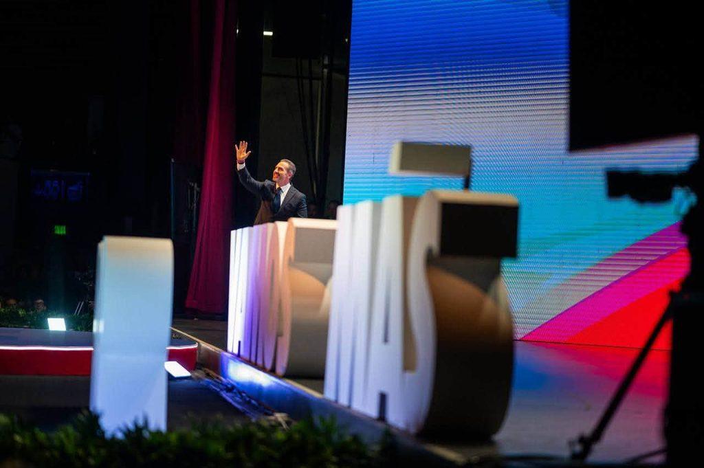 828710966_1631461765009070_8541521519877919401_n - Nuevo León Primero a Man in a Suit Waves from a Stage Beside Large White Letters, with a Colorful Led Screen Backdrop Behind Him. - Nuevo León Primero