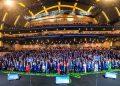 Huge Group of People in Formal Attire Posing on a Multi-tiered Stage in a Modern Auditorium; 'juntos' Signs Visible at Front. - Nuevo León Primero