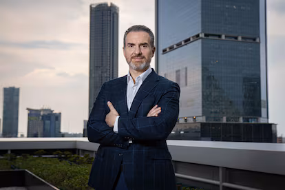 Gpyjl6gk7zcdzckujfzqcnkh6e - Nuevo León Primero Confident Businessman in a Dark Suit Stands with Arms Crossed on a Rooftop, with a City Skyline in the Background. - Nuevo León Primero