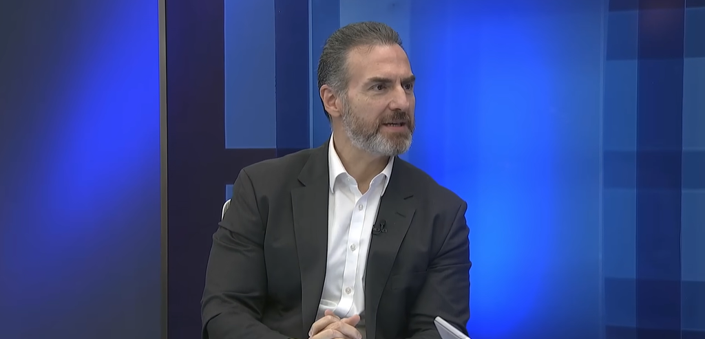 Man in a Dark Suit and White Shirt Sits in a Tv Studio with a Blue Geometric Backdrop While Speaking in an Interview. - Nuevo León Primero
